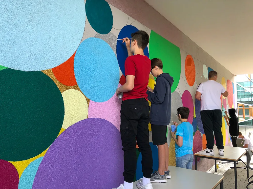 Jugendliche streichen die Kreise an die Wand.